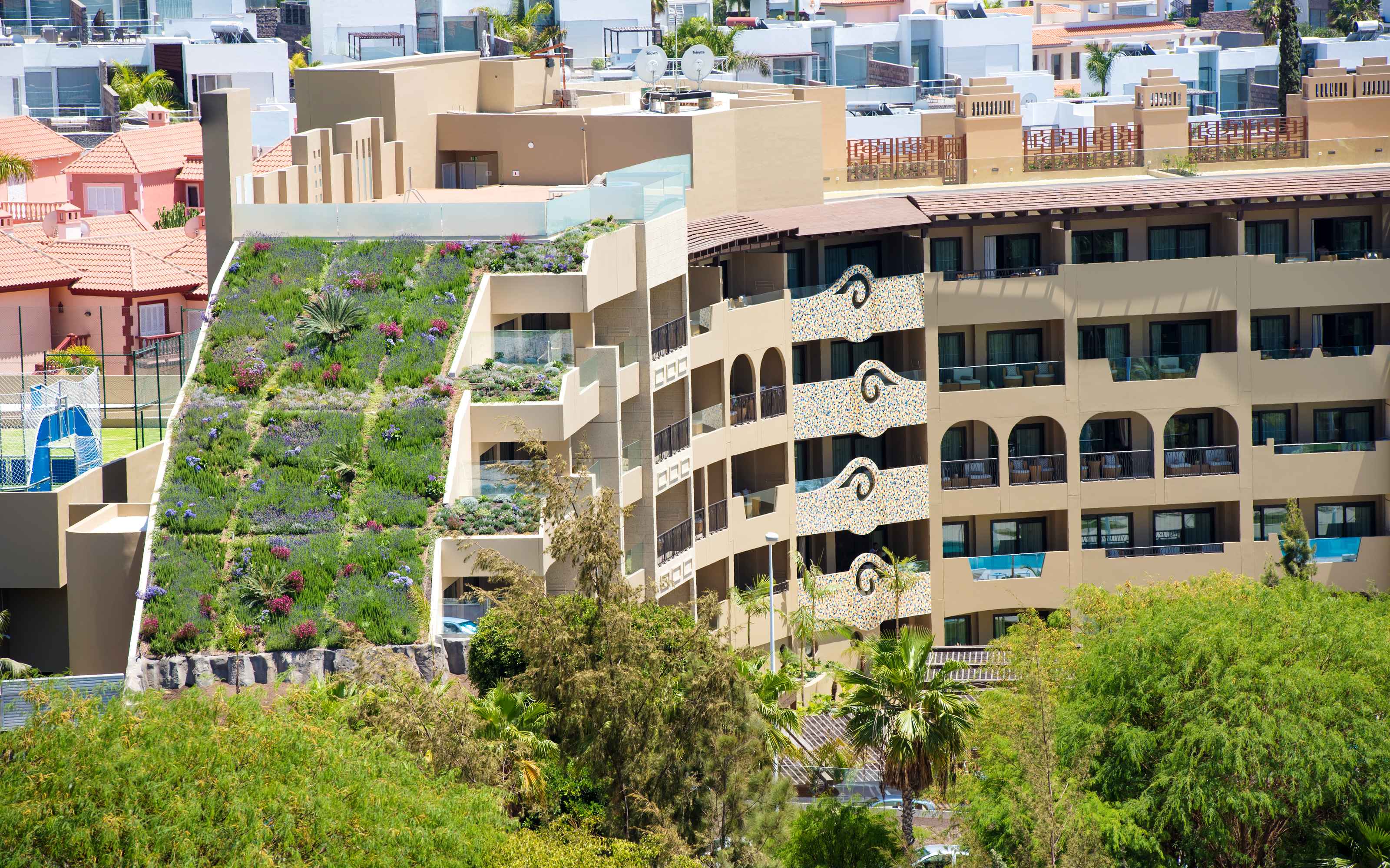 Only six months after planting, the shrubs and perennials have developed into a beautiful flower carpet. Hotel building with steep pitched green roof